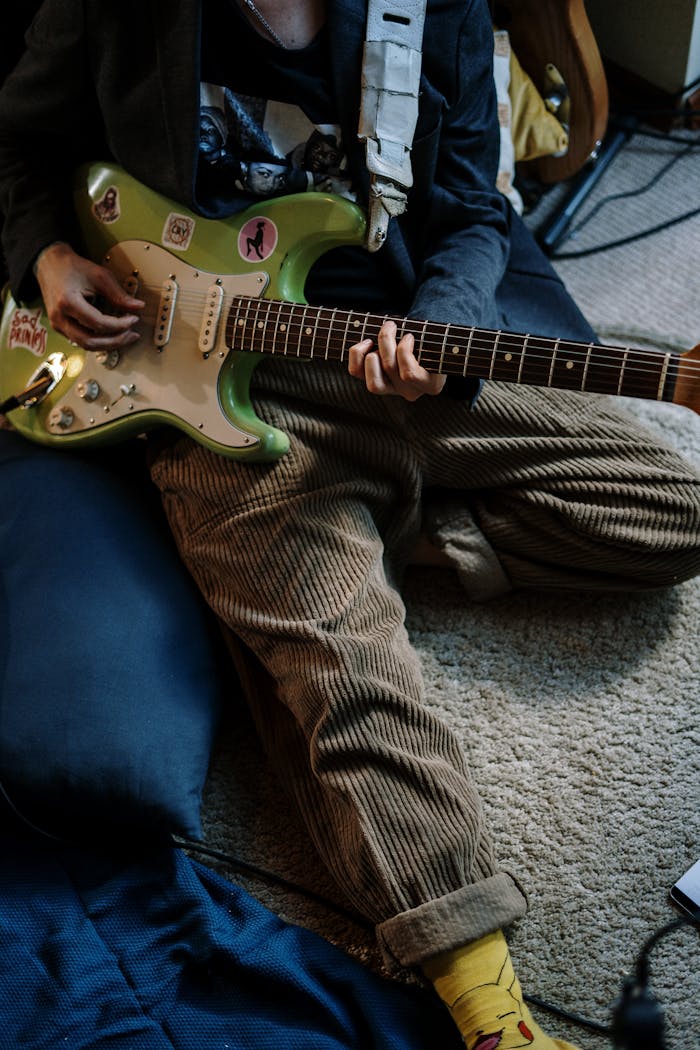 Person Playing Red and White Stratocaster Electric Guitar